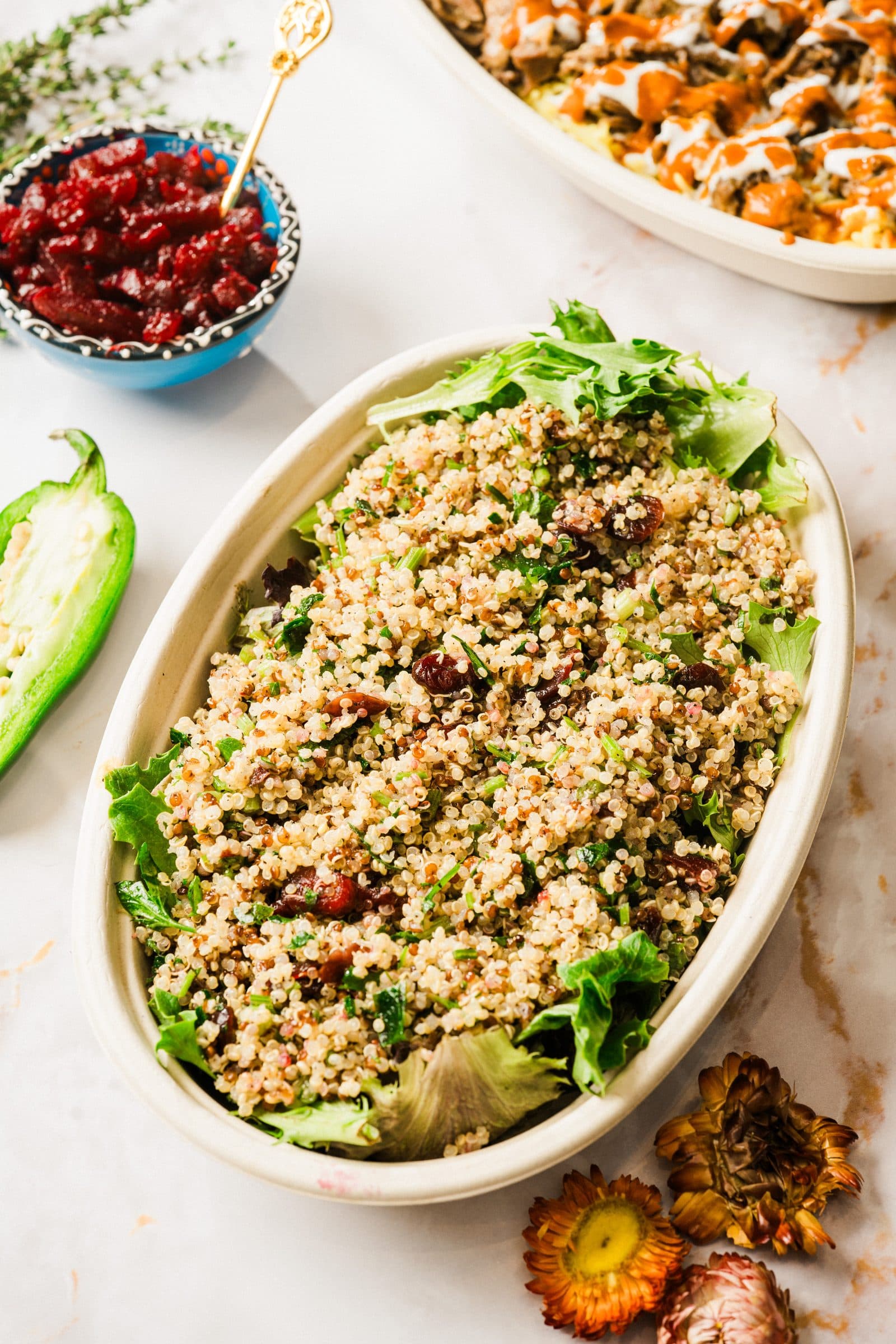 A bowl of quinoa with herbs and dried cranberries, with a gold serving spoon