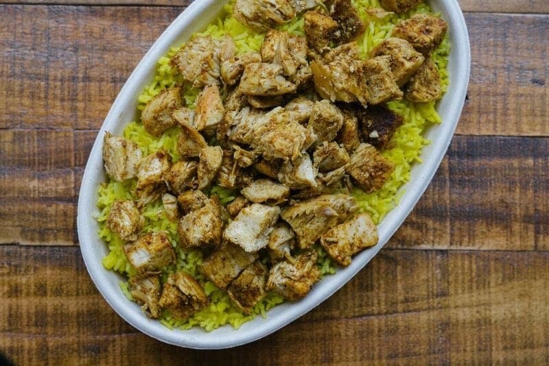 Pieces of herbed chicken served over yellow rice on an oval dish